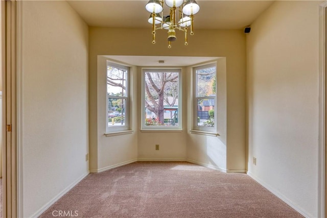 carpeted spare room with plenty of natural light and a chandelier