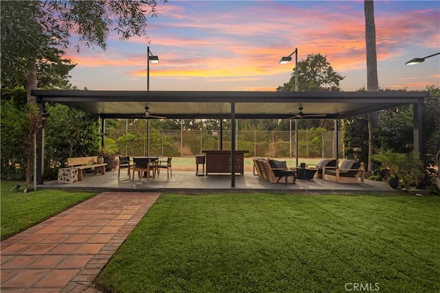 patio terrace at dusk with ceiling fan and a lawn