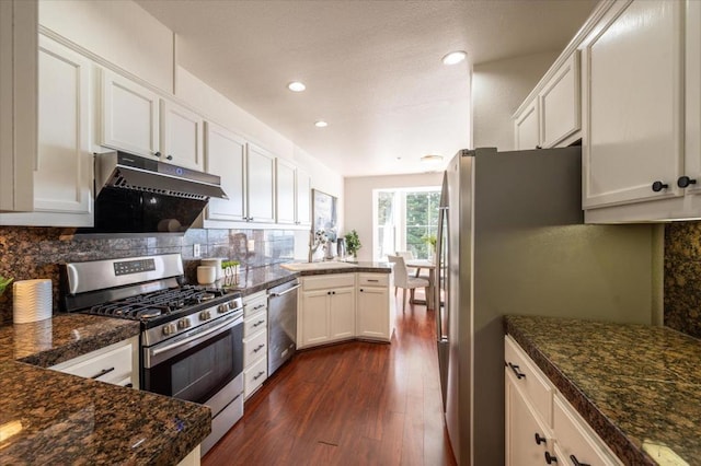 kitchen with dark hardwood / wood-style flooring, backsplash, white cabinets, and appliances with stainless steel finishes