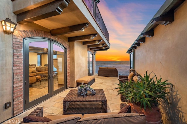 patio terrace at dusk featuring french doors and a water view