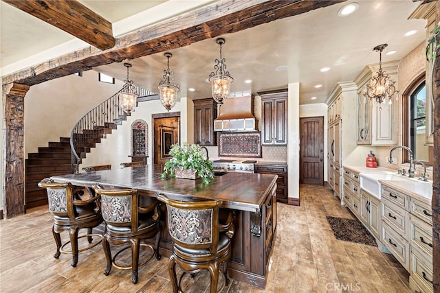 dining area featuring sink, an inviting chandelier, beam ceiling, and light hardwood / wood-style floors