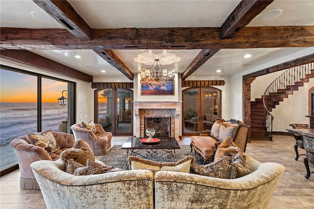 living room featuring a water view, beam ceiling, and a chandelier