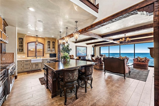 kitchen featuring stainless steel stove, decorative light fixtures, sink, light hardwood / wood-style floors, and a water view