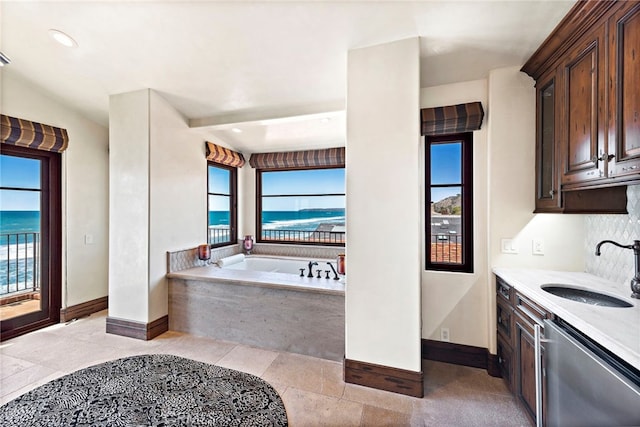 bathroom with vanity, tiled tub, and a water view