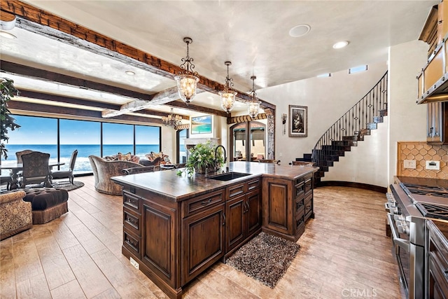 kitchen featuring dark brown cabinetry, sink, a water view, an island with sink, and high end stainless steel range oven