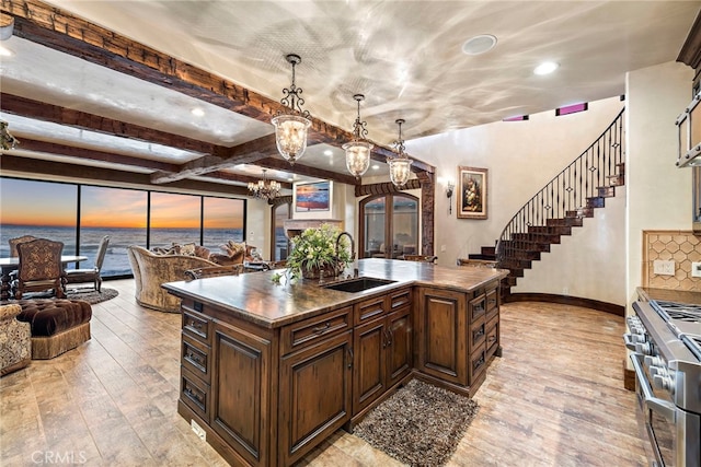 kitchen with a water view, sink, a center island with sink, and high end range