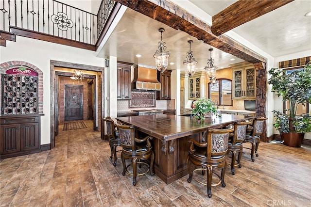 kitchen with pendant lighting, wood-type flooring, a kitchen island, and custom exhaust hood