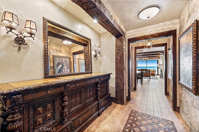 hallway with an inviting chandelier and light hardwood / wood-style flooring