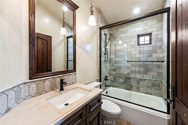 full bathroom with tasteful backsplash, vanity, bath / shower combo with glass door, and toilet