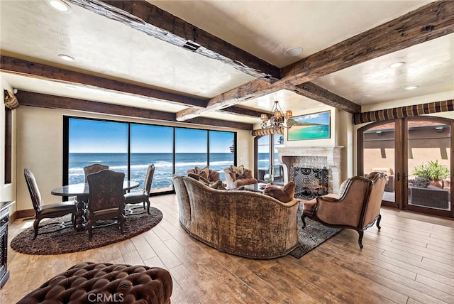 living room with beamed ceiling, a water view, a wealth of natural light, and light hardwood / wood-style floors