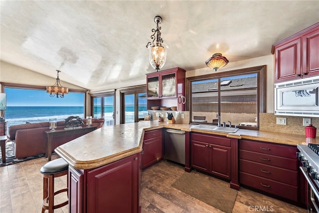 kitchen featuring a water view, appliances with stainless steel finishes, decorative light fixtures, and kitchen peninsula