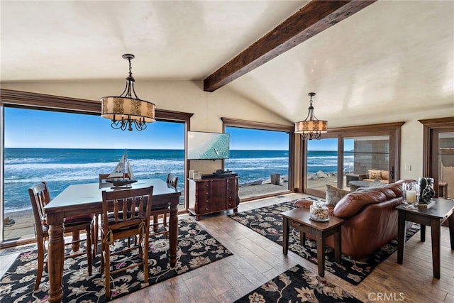 dining room featuring a view of the beach, vaulted ceiling with beams, a water view, a chandelier, and hardwood / wood-style floors