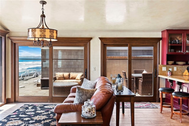 living room with a water view, light wood-type flooring, and a chandelier