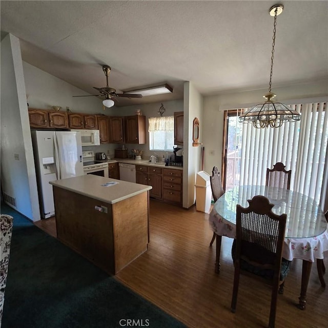 kitchen with light countertops, white appliances, a kitchen island, dark wood-style floors, and brown cabinetry