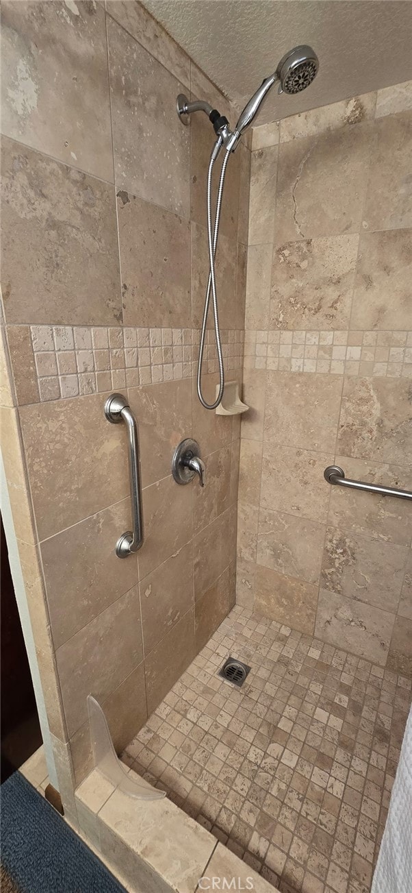 full bath with a textured ceiling and a tile shower