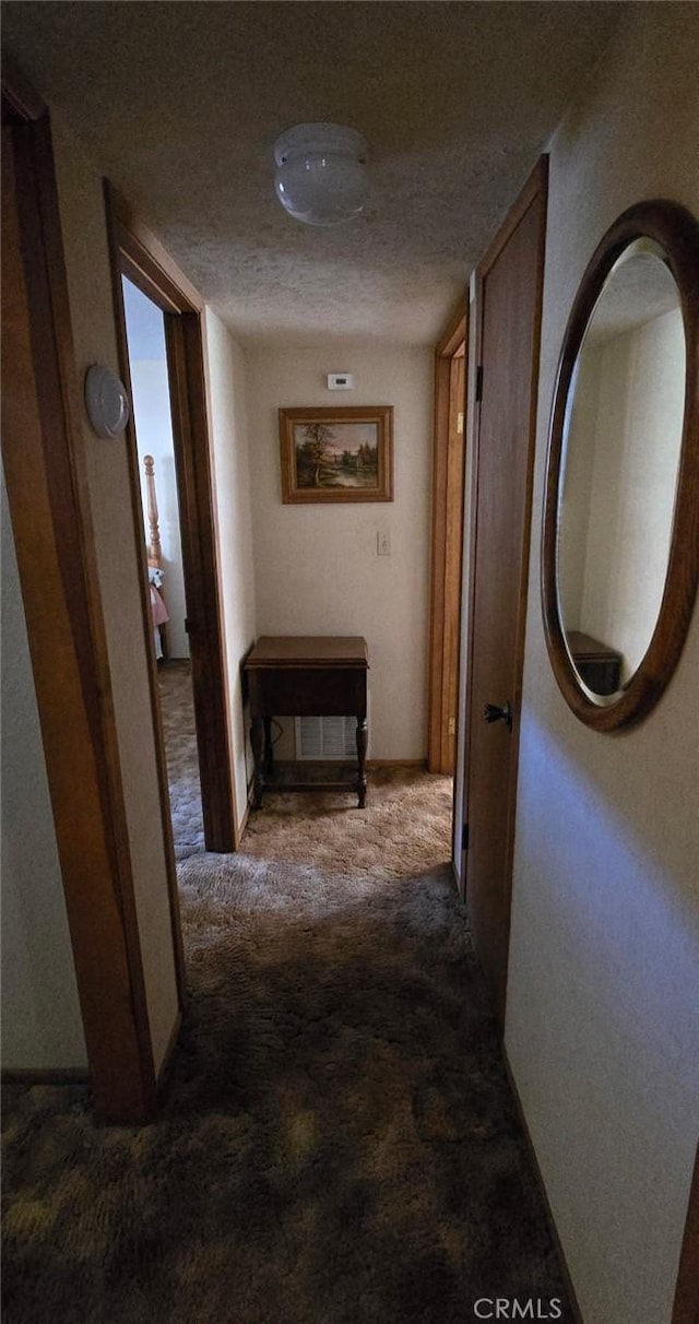 corridor with carpet and a textured ceiling