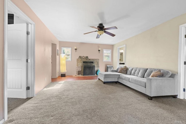 carpeted living room featuring a brick fireplace and ceiling fan