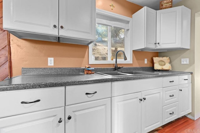 kitchen with white cabinetry, sink, and hardwood / wood-style floors