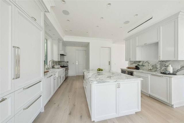 kitchen featuring light stone counters, sink, a center island, and white cabinets