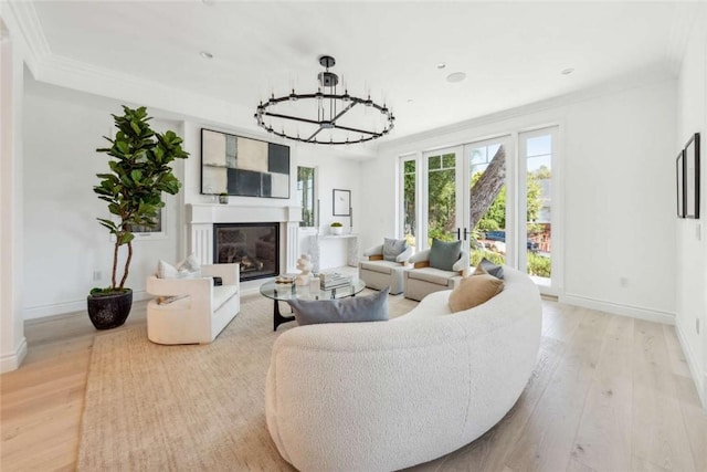 living room with ornamental molding, a chandelier, light hardwood / wood-style floors, and french doors