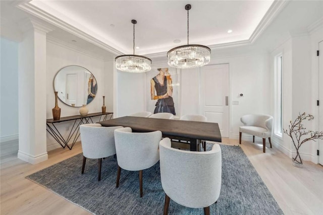 dining area with crown molding, light hardwood / wood-style flooring, and a tray ceiling