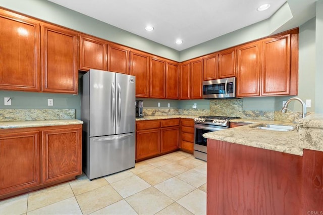 kitchen with appliances with stainless steel finishes, light stone countertops, sink, and light tile patterned floors