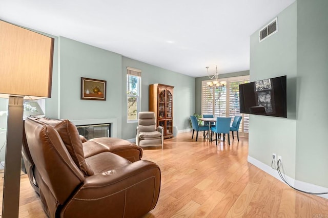 living room with a notable chandelier, a healthy amount of sunlight, and light wood-type flooring