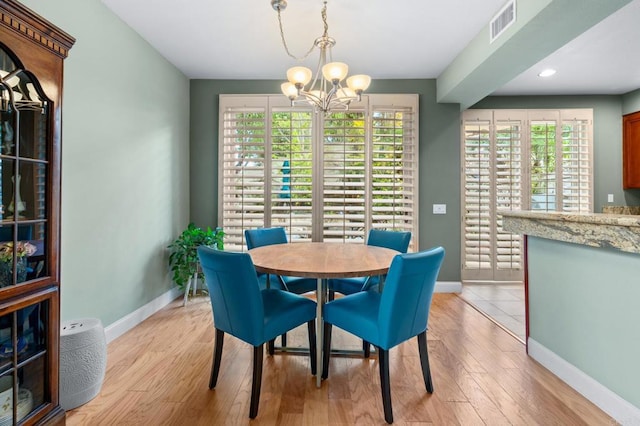 dining area with light hardwood / wood-style flooring and a chandelier