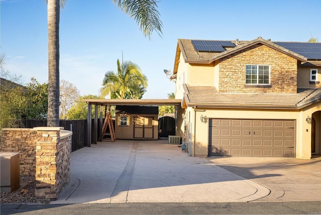 view of front of property with a garage, central AC unit, and solar panels