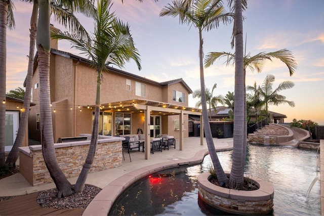 pool at dusk with an outdoor fire pit, a pergola, a patio area, and a bar