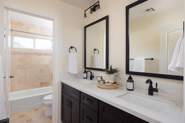 full bathroom featuring tiled shower / bath, vanity, and toilet