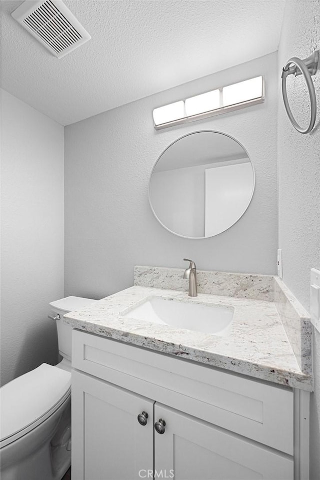 bathroom with vanity, toilet, and a textured ceiling