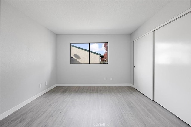 unfurnished bedroom featuring a textured ceiling, light wood-type flooring, and a closet