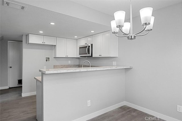 kitchen featuring pendant lighting, sink, white cabinetry, dark hardwood / wood-style floors, and kitchen peninsula