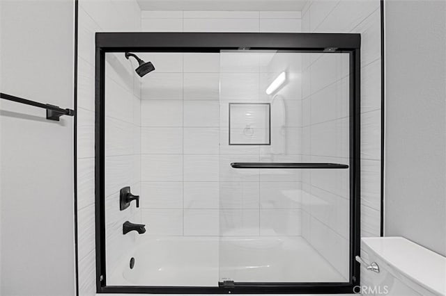 bathroom featuring shower / bath combination with glass door and toilet