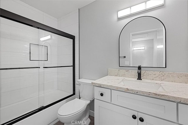 full bathroom featuring vanity, shower / bath combination with glass door, and toilet