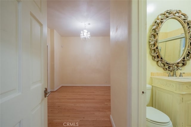 hallway featuring an inviting chandelier, sink, and light wood-type flooring