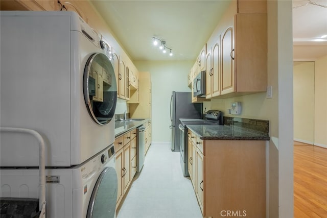 kitchen with electric range oven, sink, stacked washer and clothes dryer, stainless steel dishwasher, and track lighting