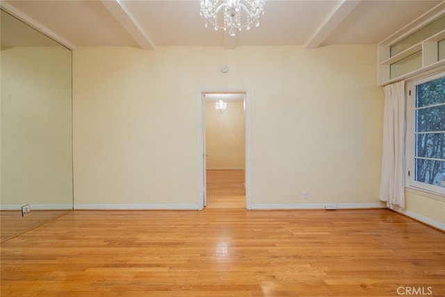 empty room with light hardwood / wood-style flooring and a notable chandelier