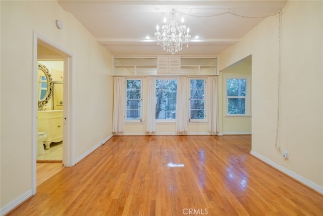 spare room with wood-type flooring and an inviting chandelier