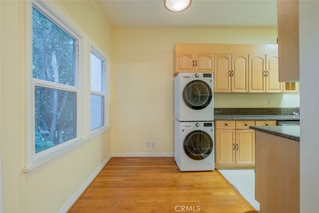 washroom with light hardwood / wood-style flooring, cabinets, and stacked washing maching and dryer