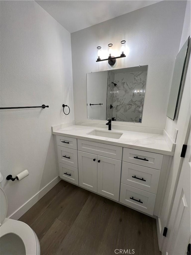 bathroom featuring hardwood / wood-style flooring, vanity, walk in shower, and toilet