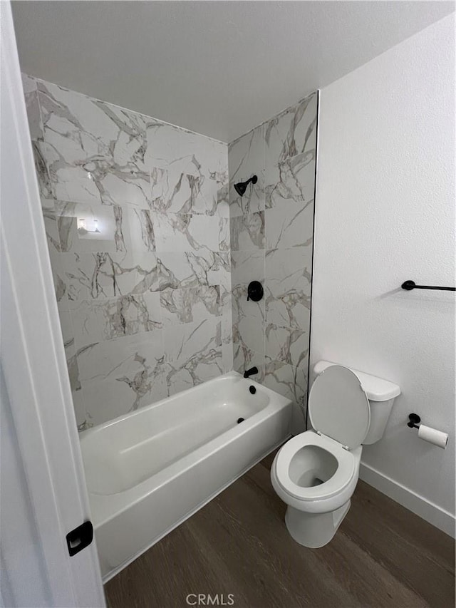 bathroom with hardwood / wood-style floors, tiled shower / bath combo, and toilet