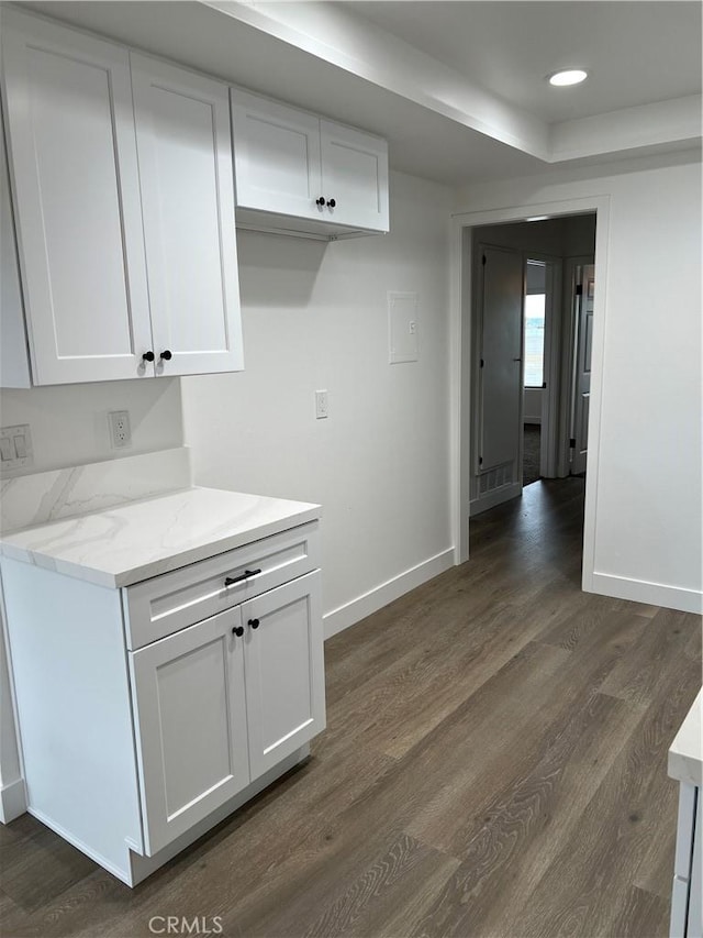 kitchen featuring light stone countertops, dark hardwood / wood-style floors, and white cabinets