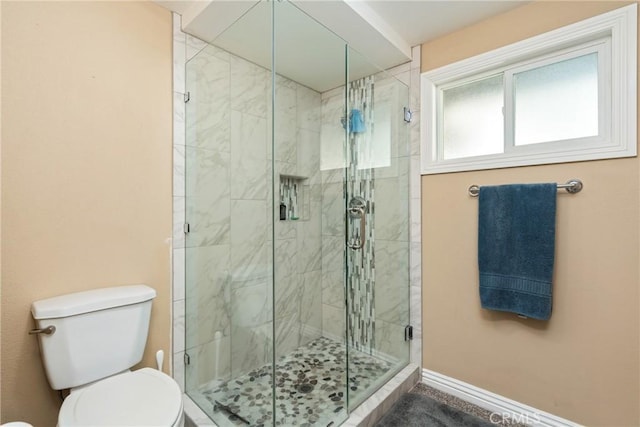 bathroom with a shower with door and toilet