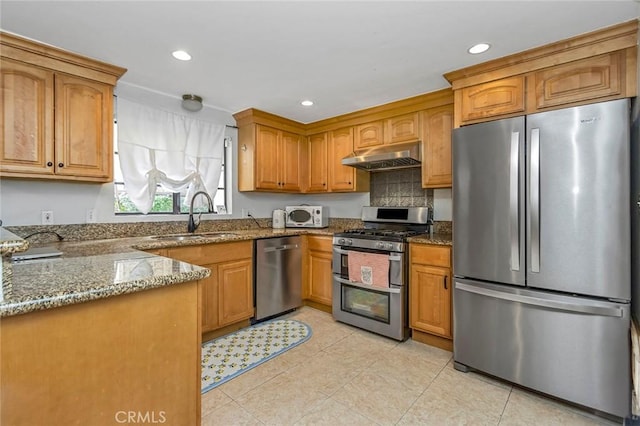 kitchen with sink, light tile patterned floors, stainless steel appliances, and dark stone counters