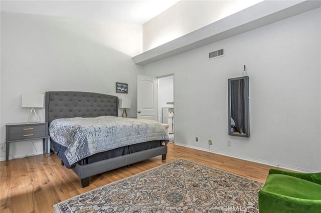 bedroom with connected bathroom and hardwood / wood-style floors