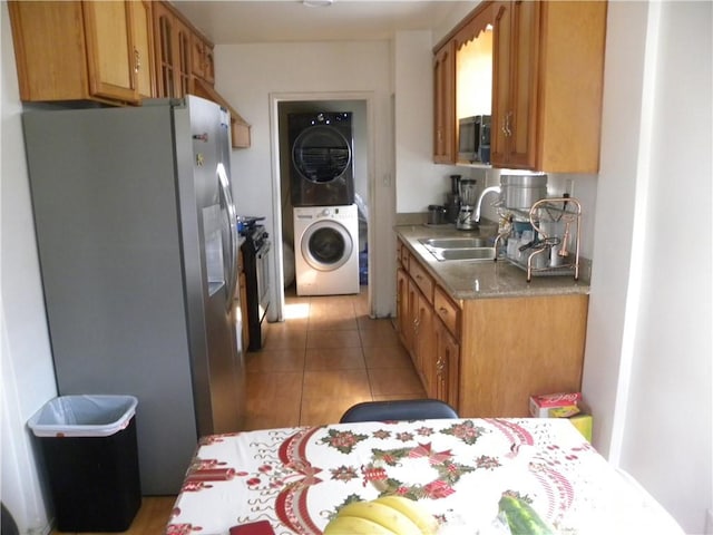 kitchen featuring stacked washer and dryer, stainless steel appliances, sink, and light tile patterned floors