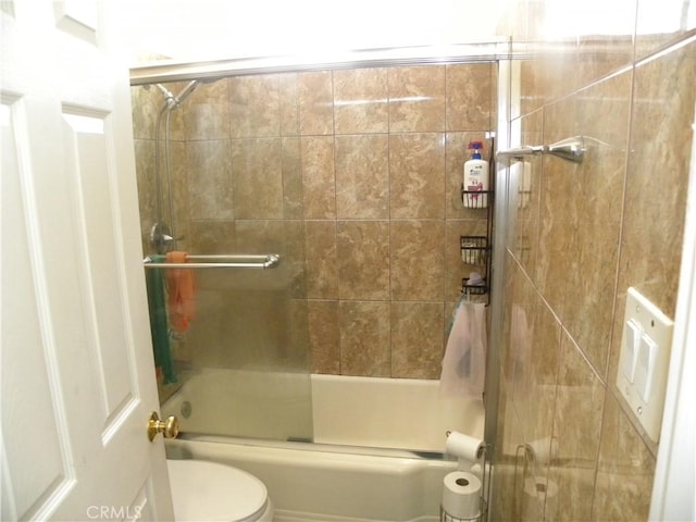 bathroom with toilet and shower / bath combination with glass door