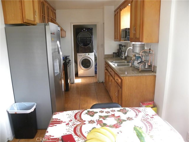 kitchen with sink, stainless steel fridge, light tile patterned flooring, and stacked washing maching and dryer